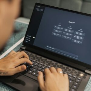 Close-up of a person typing on a laptop displaying the ChatGPT interface, emphasizing modern technology use.